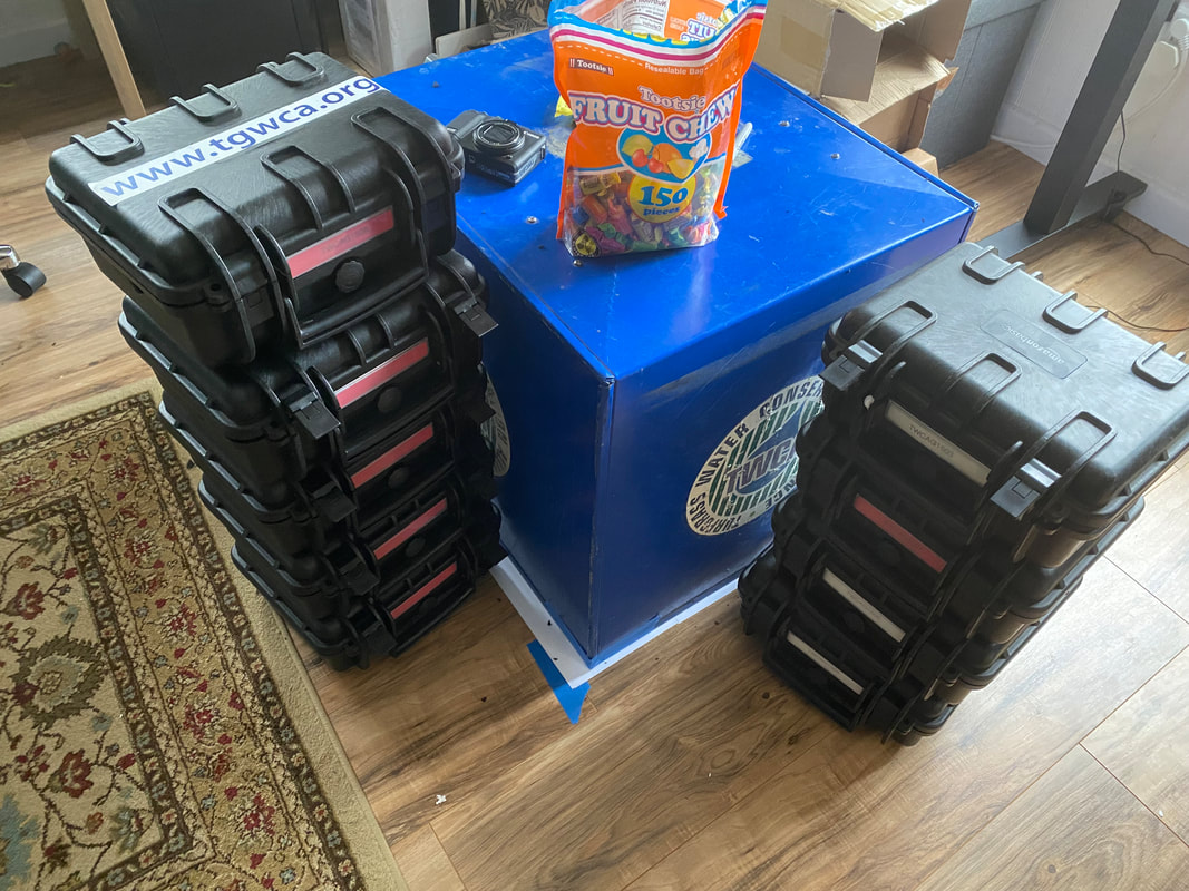 PictureCamera travel boxes stacked around a blue DIA box w/ a bag of fruit chews featured